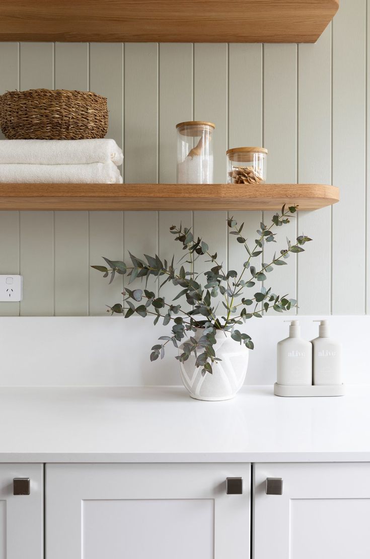 a white vase filled with flowers sitting on top of a counter next to two towels