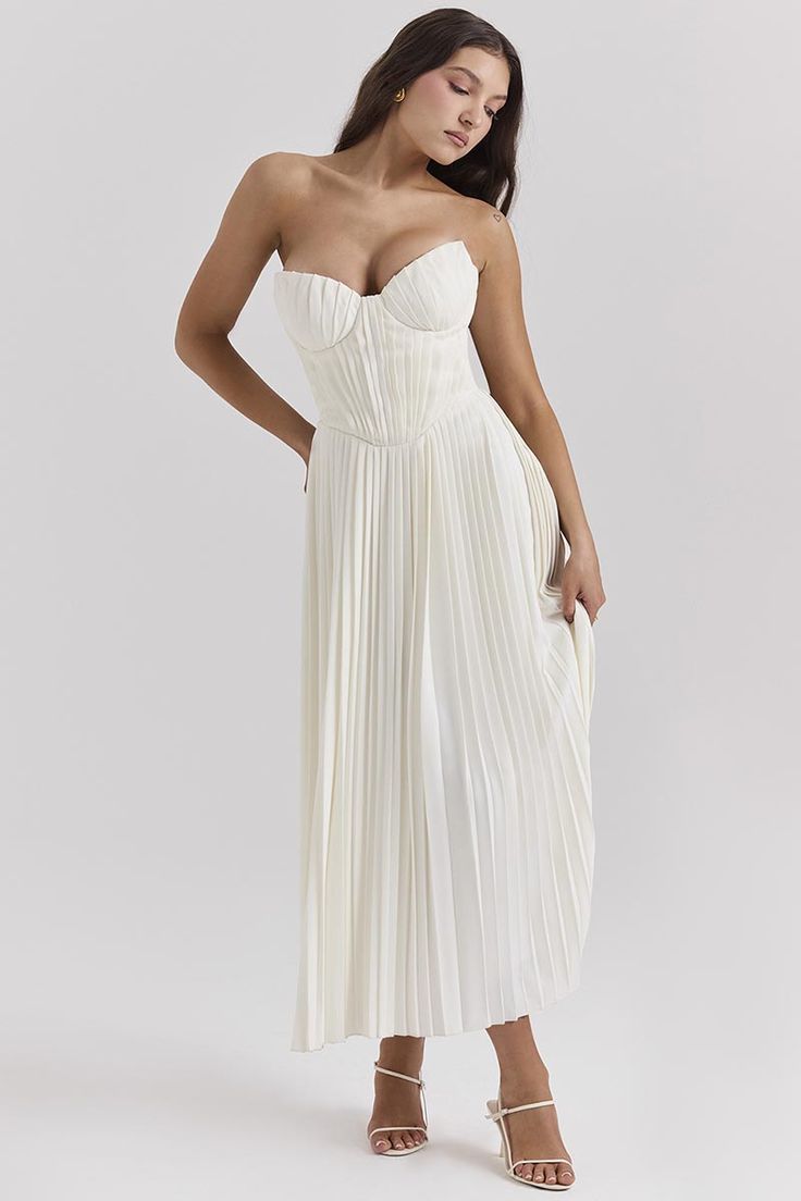 a woman is wearing a white dress with pleating