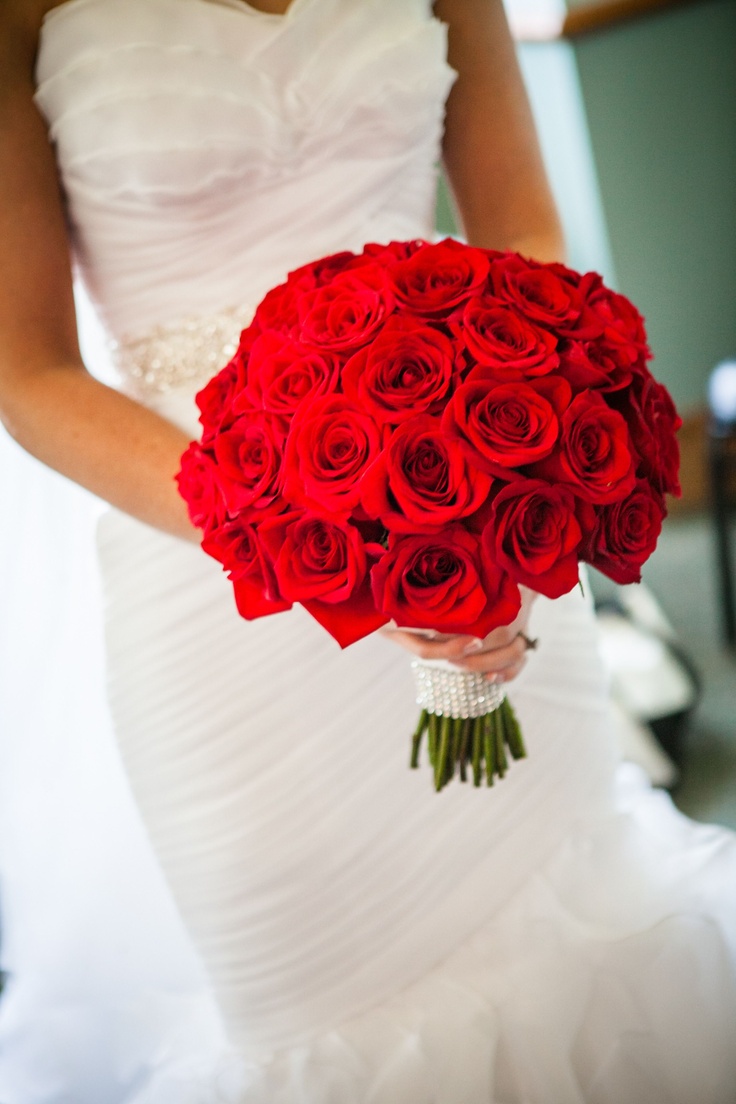 a bride holding a bouquet of red roses