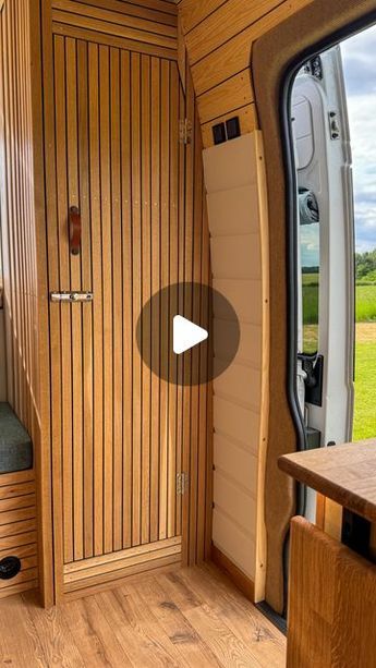 the inside of an rv with wood paneling and doors open to let in natural light