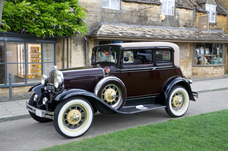 an antique car is parked on the side of the road in front of a building