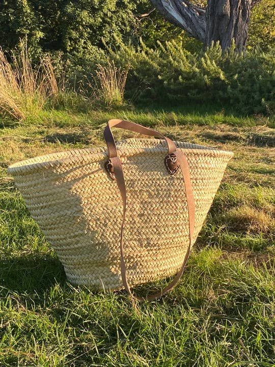 a large straw bag sitting in the grass