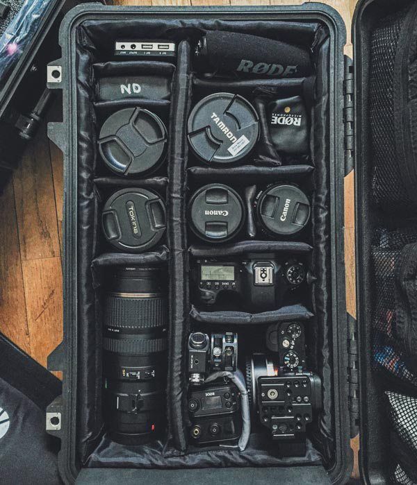 an open camera case sitting on top of a wooden floor next to other cameras and accessories