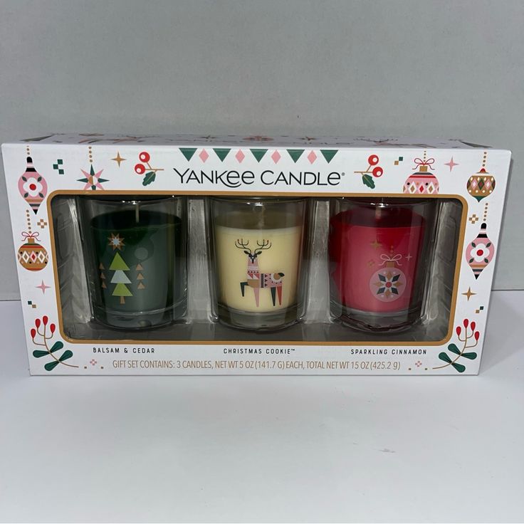 three candles in a box with christmas decorations