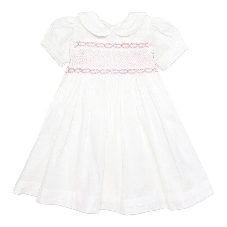 This gorgeous traditional white cotton dress is a perfect addition to your child's wardrobe.  It can be dressed up or down.  Ideal for any occasion with a stunning deep hand smocked central panel in pink adding a beautiful classic feel.  Made with love it features a peter pan collar, a gorgeous puff sleeve with pleated turn back cuffs finished off with buttons down the back.  100% Cotton Fully lined 100% Cotton Machine wash at 30 degrees Wash with similar colours Classic Daywear Dress With Smocked Bodice, Pink Short-sleeved Dress With Smocked Cuffs, Pink Short Sleeve Dress With Smocked Cuffs, Classic Spring Smocked Dress With Smocked Cuffs, Pink Smocked Dress With Smocked Cuffs For Daywear, Pink Cotton Dress With Smocked Bodice, Elegant White Smocked Dress For Baptism, Spring Classic Smocked Dress With Smocked Bodice, Classic Smocked Dress With Smocked Bodice For Spring