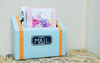 a blue mailbox with flowers in it sitting on a counter next to a wall