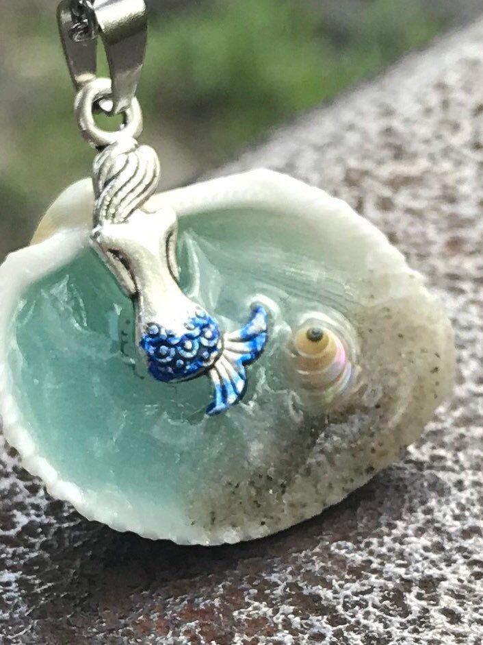 "Mermaid in a Shell Necklace, Beach Lover Gift, Mythical Fun Jewelry, Gift for her, unique necklaces for women, Gifts for Sister, Beach Wedding Handmade and unique Mermaid in a Shell necklace. Mermaid Bath This beautiful Mermaid in a shell necklace has been handmade by me using real sand a real seashell and resin. Be Unique, have an original design, This necklace will be a conversational piece. The water also glows in the dark if you leave it under a UV lamp or in the sunlight for a few minutes. Blue Charm Necklaces For The Beach, Whimsical Blue Pendant Jewelry, Personalized Adjustable Blue Charm Necklaces, Bohemian Mermaid Necklace For Gifts, Bohemian Mermaid Necklace Gift, Whimsical Blue Charm Jewelry, Whimsical Blue Jewelry With Charms, Personalized Turquoise Jewelry For Beach, Personalized Themed Blue Jewelry