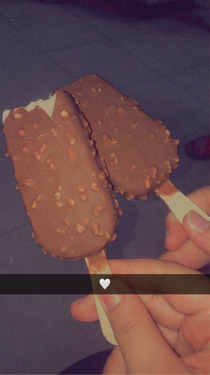 someone is holding an ice cream on a stick with chocolate and nuts in the middle