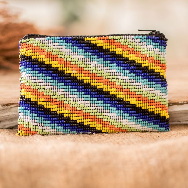 Intricately embellished with a medley of dainty glass beads in an enchanting palette of blue, aqua, green, orange, yellow, black and white, this vibrant handcrafted coin purse is imbued with the skillful artistry of the members of the Santiago Atitlan Women's Group in Guatemala. The striped and fully lined purse elegantly secures your valuables with a zippered closure, providing a fashionable haven for your bills, change, credit cards and every essential that deserves a touch of extraordinary be Multicolor Coin Purse With Zipper As Gift, Multicolor Pouch Coin Purse As Gift, Handmade Multicolor Coin Purse For Everyday Use, Handmade Multicolor Coin Purse, Handmade Multicolor Bohemian Coin Purse, Bohemian Handmade Multicolor Coin Purse, Bohemian Multicolor Handmade Coin Purse, Handmade Multicolor Coin Purse Pouch, Handmade Multicolor Pouch Coin Purse