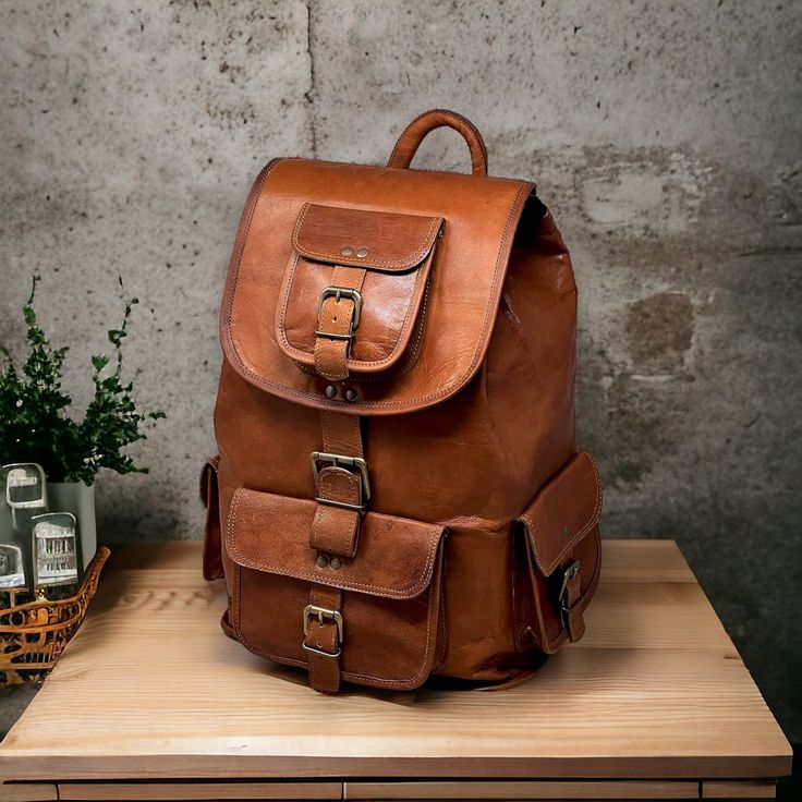 a brown leather backpack sitting on top of a wooden table