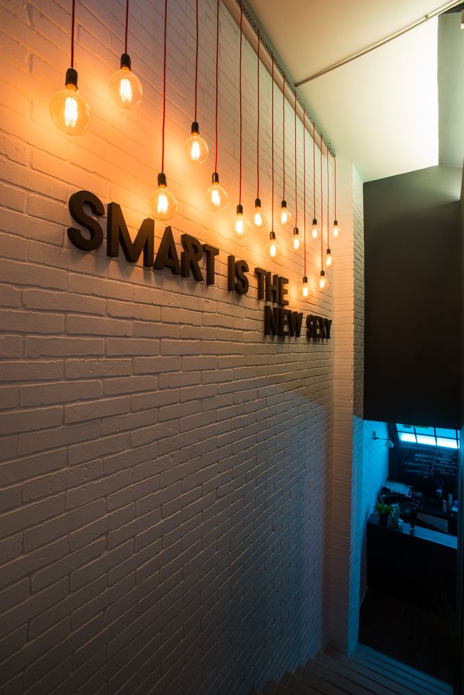 a white brick wall with lights hanging from it and the words smart is the new black