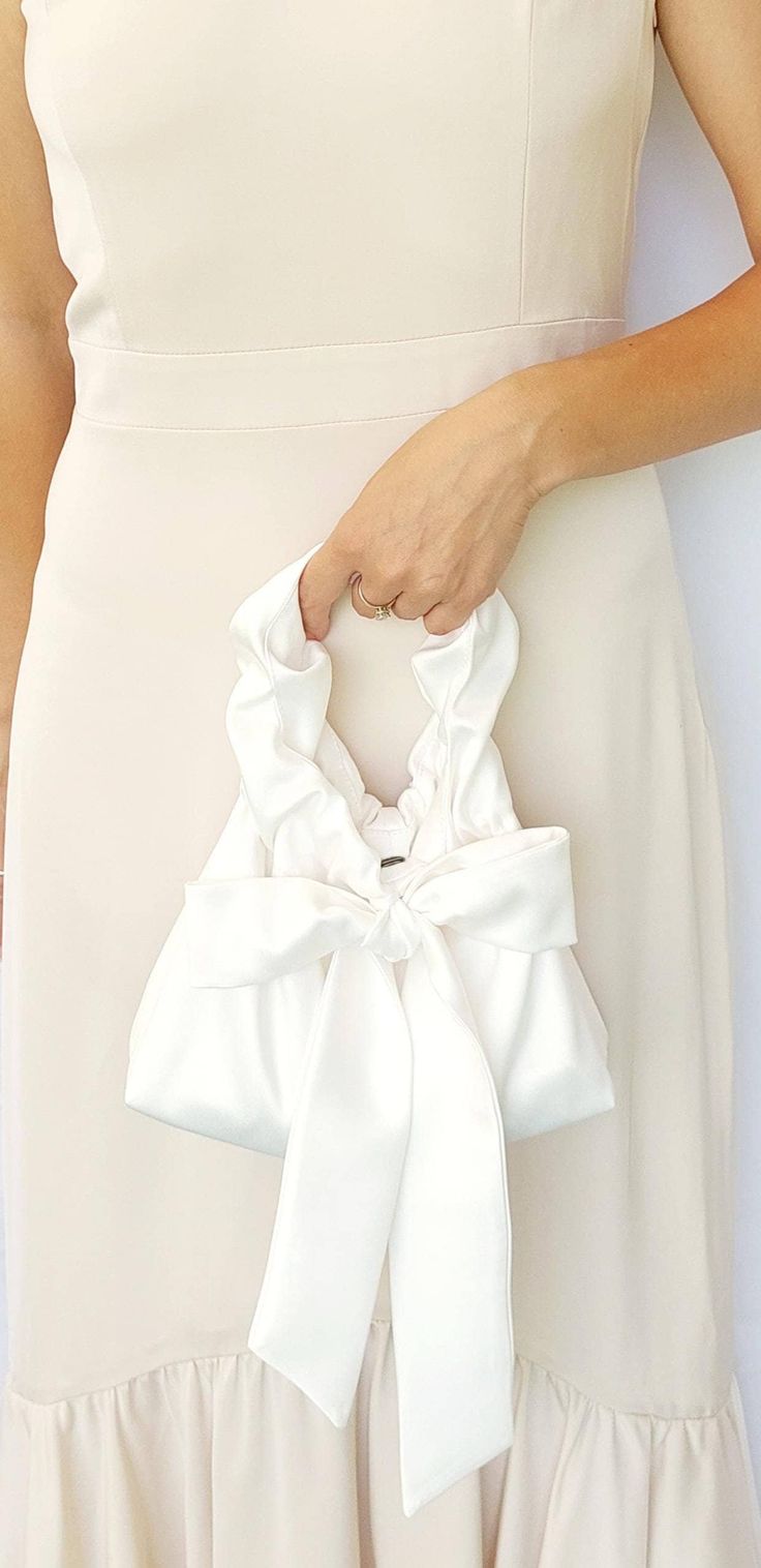 Ivory Bridal Clutch Bag,Satin Bridal Purse,Evening handbag,Silk Small Elegant Bow Bag, Ivory Color bag,Gift for bride,occasion clutch bag Attention! Dear Brides, please note that when choosing a color, the white bag is suitable only for a snow-white wedding dress. If your dress has a warmer shade, it is better to choose the ivory color. I invite you to check out this charming handbag for women, which is made of exquisite satin (satin) and is designed to emphasize your unique beauty and elegance. Luxury White Reception Bag, Elegant Bridal Accessories With Satin Bow, Feminine Beige Evening Bag, Beige Feminine Evening Bag, Elegant White Handheld Evening Bag, Elegant White Evening Bag With Pearl Handle, White Clutch Evening Bag, Elegant White Clutch For Events, Formal Feminine Cream Bag