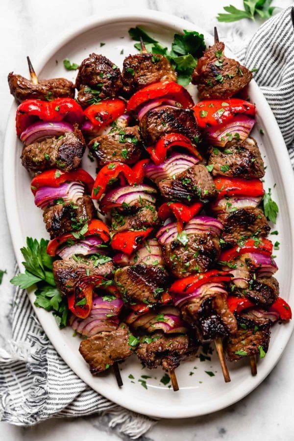 meat kabobs on skewers with red onions and parsley garnish