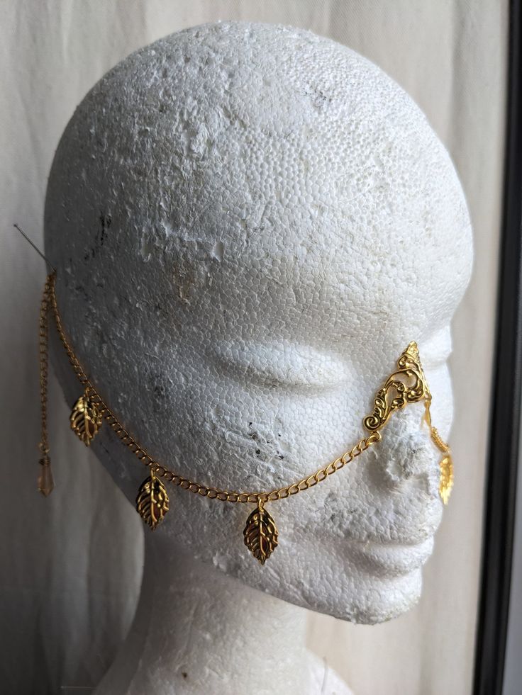 a white mannequin head with gold jewelry on it