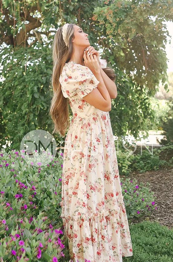 a woman in a floral dress is drinking from a cup and looking up into the sky