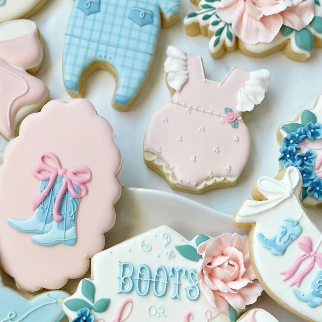 decorated baby shower cookies on a plate with blue and pink decorations around them, including booties