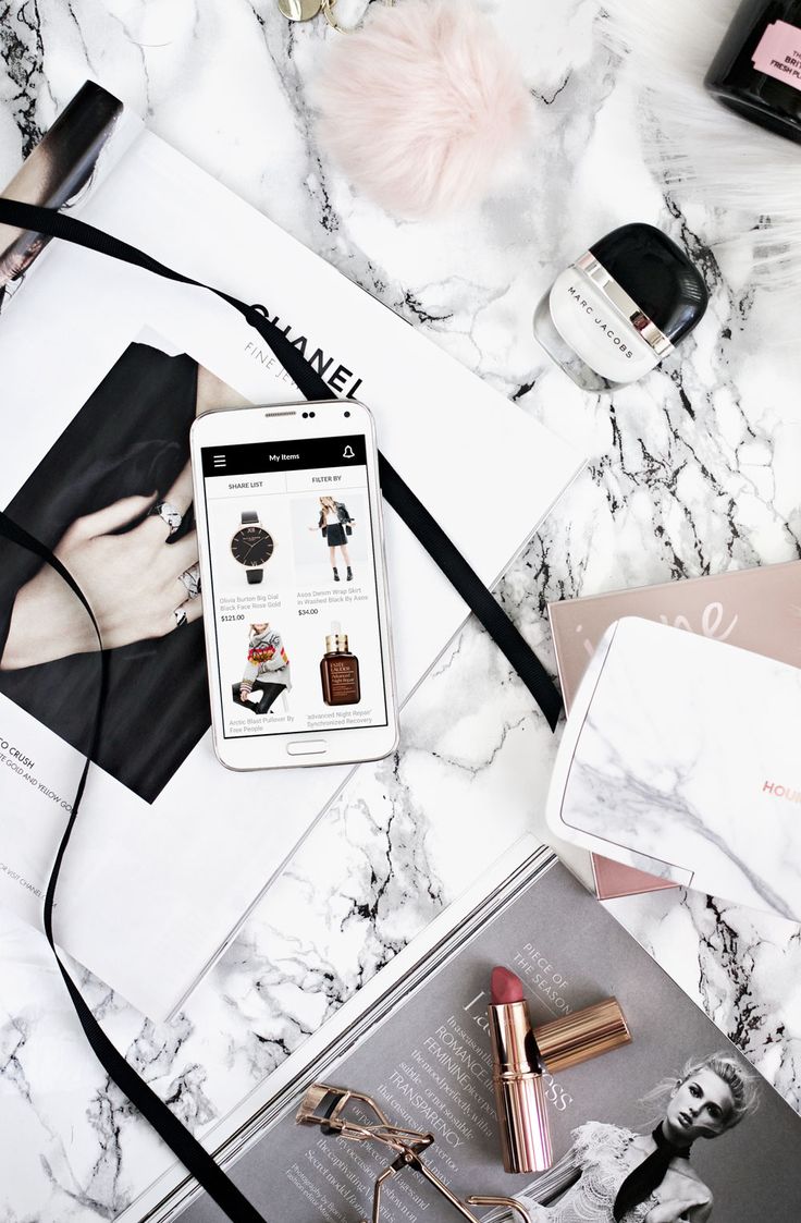 the contents of a woman's purse and her cell phone on a marble table