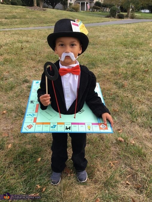 a young boy in a tuxedo and top hat holding an electronic board game