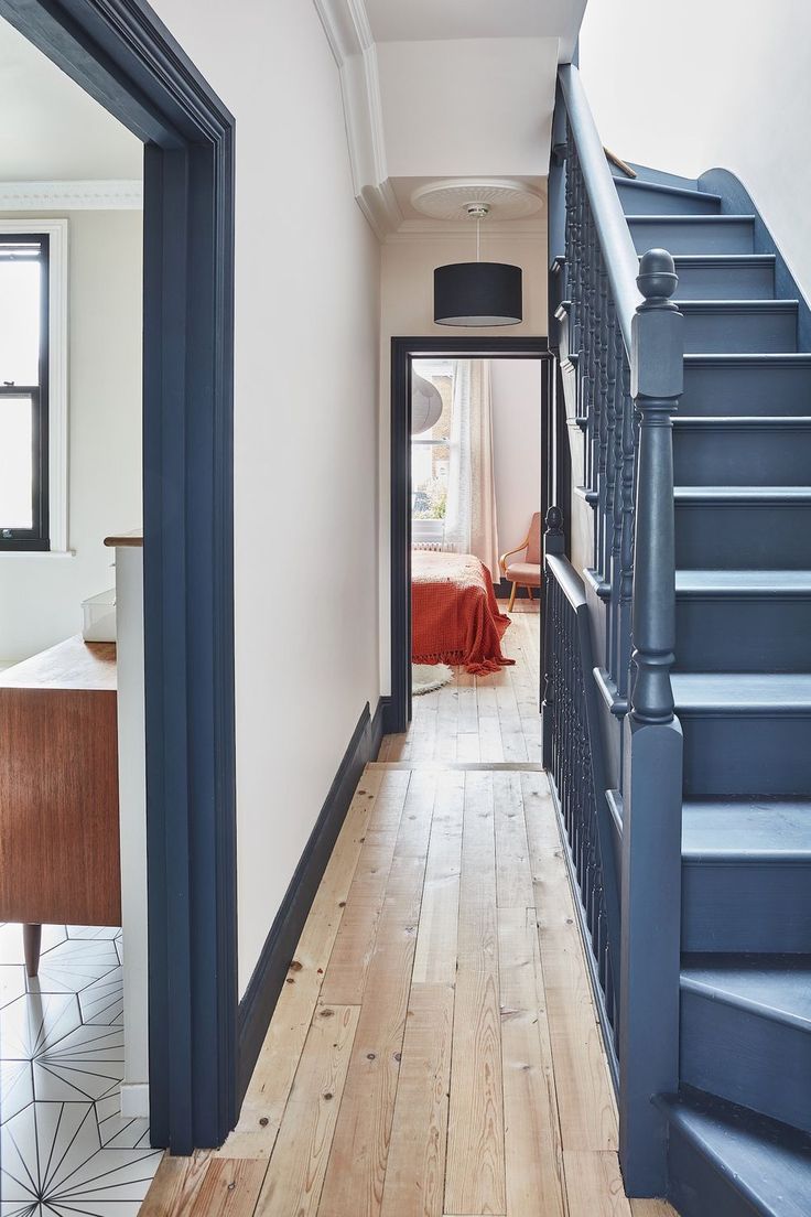 the hallway is painted white and has blue stairs leading up to it's bedroom