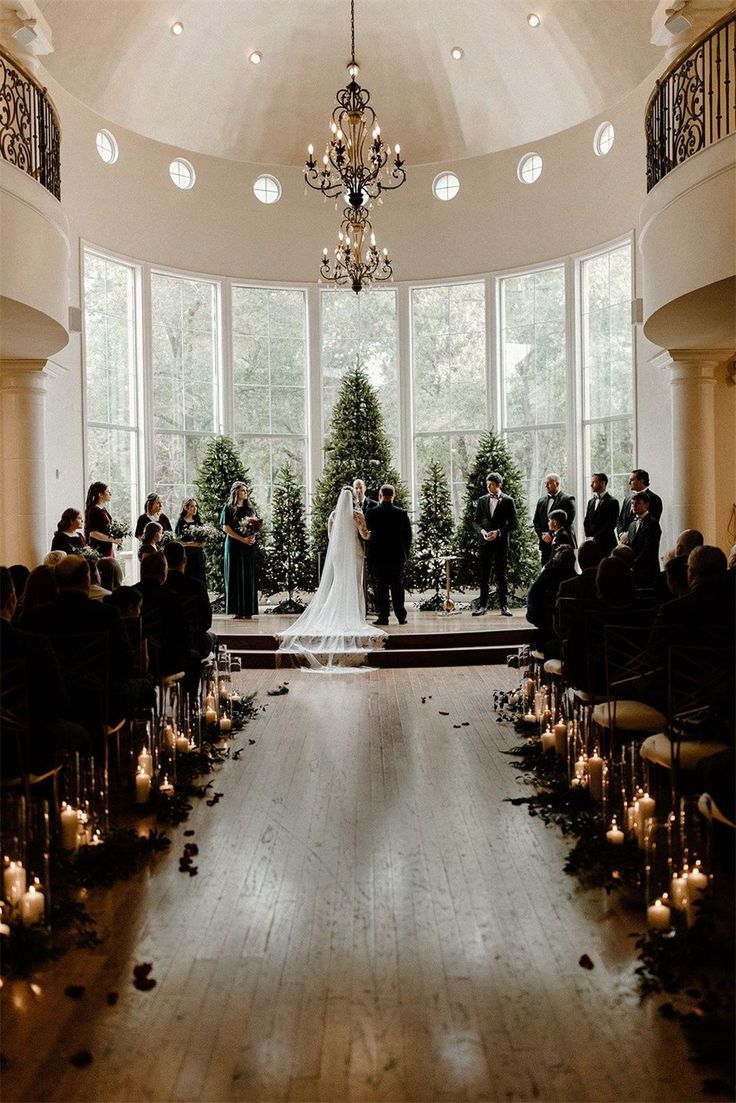 a bride and groom standing at the alter in front of their wedding party, surrounded by candles