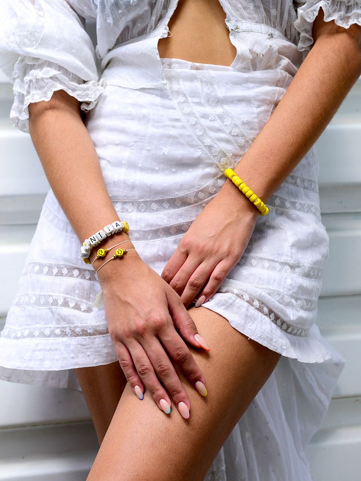 Show off your sunny disposition with the High Hopes Bracelet! This cheerful accessory features a white adjustable threadwork accented with yellow glass beads and cute ceramic smiley faces. 6" Adjustable white threadwork Drawstring closure (extendable up to 8") Gold plated brass hardware Glass charms Ceramic charms Handmade in New York City and Puerto Rico. Due to the handmade nature of our products, some charms may vary in color and style or be replaced if unavailable. Please allow 5-7 business Trendy Yellow Jewelry With Letter Beads, Trendy Yellow Beaded Bracelets With Letter Beads, Everyday Yellow Beaded Friendship Bracelets, Gold Letter Beads Friendship Bracelets For Summer, Casual Yellow Bracelets With Letter Beads, Gold Friendship Bracelets With Letter Beads For Summer, White Beaded Bracelets For Spring Vacation, Adjustable Yellow Friendship Bracelets With Letter Beads, Trendy Adjustable Yellow Friendship Bracelets