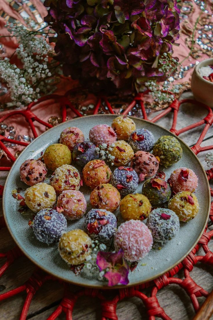 a plate filled with different colored donuts on top of a table next to flowers