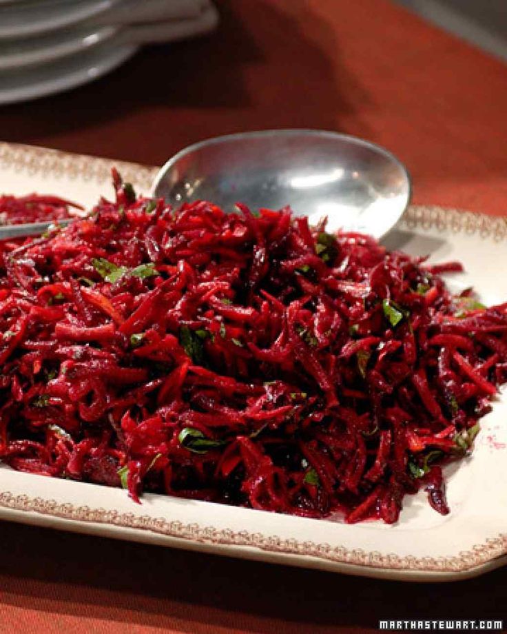 there is a plate full of red rice and spoons on the table next to it