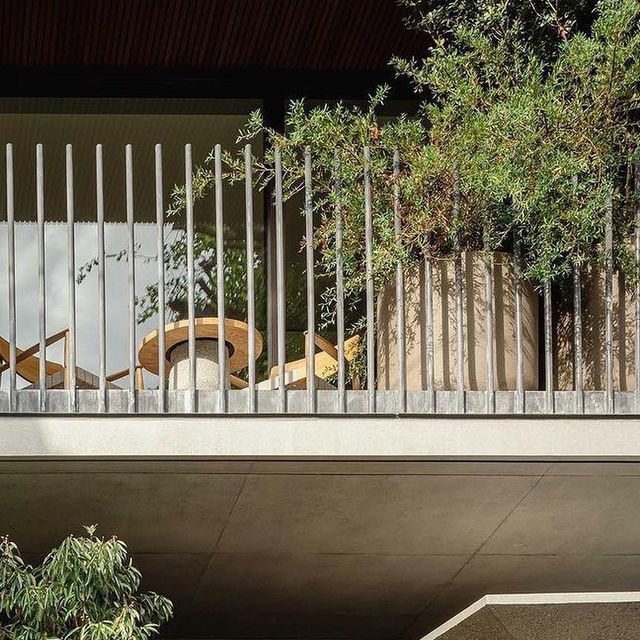 an apartment balcony with metal railings and trees on the other side in front of it