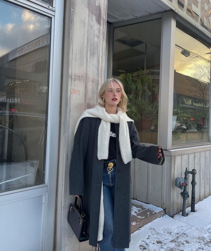 a woman standing in front of a building with her hand on the side of the door