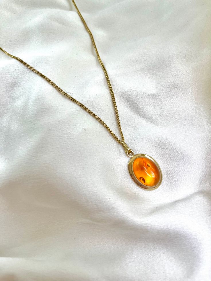 This gorgeous 9ct yellow gold oval amber cabochon pendant on a 9ct Italian 18 inch chain is a standout piece. The pendant is transparent with sun spangle inclusions, and a medium-dark orange-yellow colour. Pendant description - The gold setting is hallmarked '375', 'y' for date, 'AC' for makers mark, however the assay stamp is not clearly readable. The pendant weighs 2.5g Gem - The oval amber cabochon measures 12.50 x 17.30 x 6.60mm Chain description - 9ct yellow gold vintage Italian chain stamp Italian Chain, Yellow Colour, Amber Necklace, Dark Orange, Cabochon Pendant, Oval Cabochon, Vintage Italian, Orange Yellow, Makers Mark