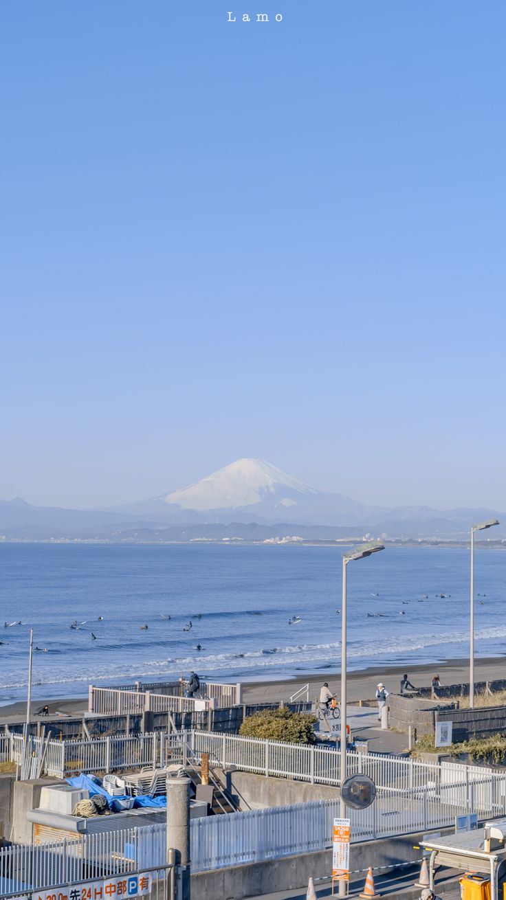 an airplane flying over the ocean with mountains in the background