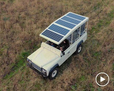 a small car with a solar panel on the roof is parked in a grassy field