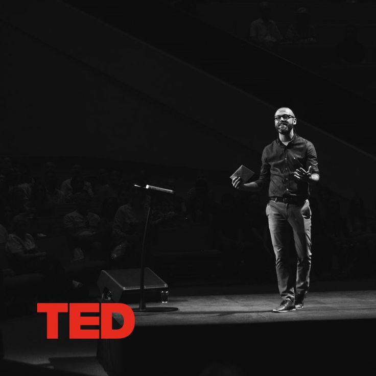 a man standing on top of a stage holding a microphone in front of an audience