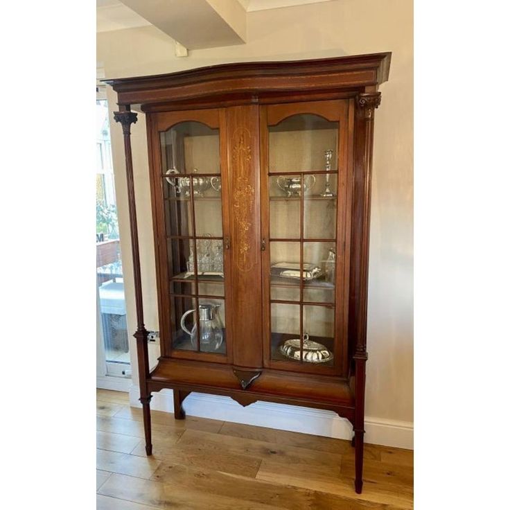 an old fashioned china cabinet with glass doors