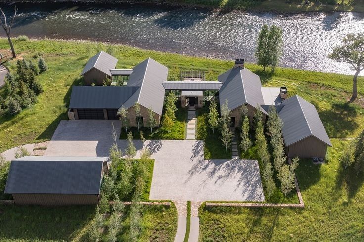 an aerial view of a house in the middle of a field with trees and grass