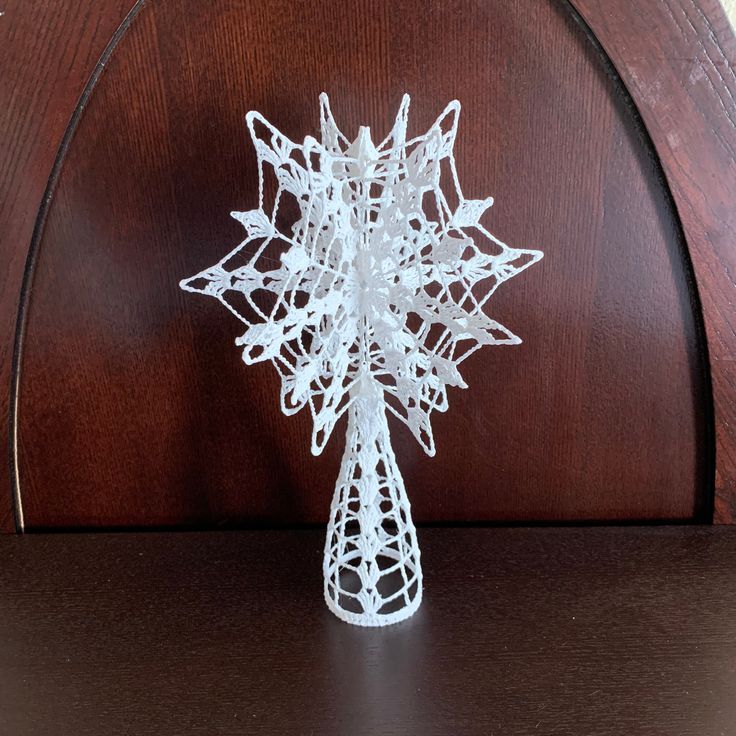 a white wire snowflake sitting on top of a wooden shelf