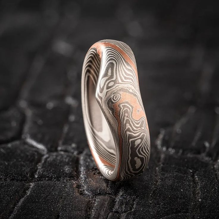 "* Price may vary depending on ring size, please inquire with us directly with your needed size for accurate pricing! This Mokume Gane ring was contoured and shaped to create this unique band shape and style. The ring is shown in the Twist pattern and the Ash Palette with a low dome profile and satin finish. The Ash palette features a metal combination of Palladium and Sterling Silver, and this ring has an added red gold stratum for a touch of contrast. Pattern: Twist Palette: Ash Finish: Satin Profile: Low Dome  Width Shown: 7mm-2.5mm taper Size Shown: 5.25 Add On: Contour, Red Gold Stratum Price does NOT include stones, setting fees. Contouring fee can vary by custom order, please inquire with us directly if you'd like a contoured band! We care about customer service and would like to he Mokume Gane Metal, Mokume Gane Ring, Contrast Pattern, Ring Inspiration, Twist Pattern, Unique Bands, Mokume Gane, Pattern Ring, Nature Inspired Design