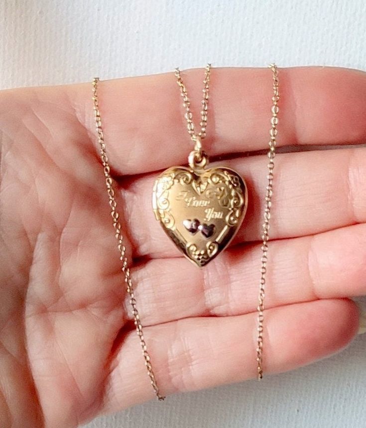 "You are looking at a vintage 1960's 14K gold fill heart shaped locket pendant on chain. The locket has engraved words \"I love You\" and opens up to insert a photo of a special person/s. Wonderful piece of sentimental jewelry ready to hold two photos. The locket has smooth back surface and floral motif with silver tone hearts. Measurements: 7/8\" x 3/4\".  Hung on gold over sterling silver 18\" delicate chain finished with a round spring clasp. A lovely picture locket to add to your collection Vintage Charm Heart Pendant Jewelry For Anniversary, Heirloom Heart-shaped Jewelry With Vintage Charm, Vintage Charm Heart-shaped Yellow Gold Jewelry, Victorian Brass Necklace With Heart Charm, Yellow Gold Heart Jewelry With Vintage Charm, Valentine's Day Medallion Necklace With Vintage Charm, Valentine's Day Vintage Charm Medallion Necklace, Vintage Heart Pendant Necklace For Anniversary, Vintage Charm Heart Pendant Jewelry For Keepsake