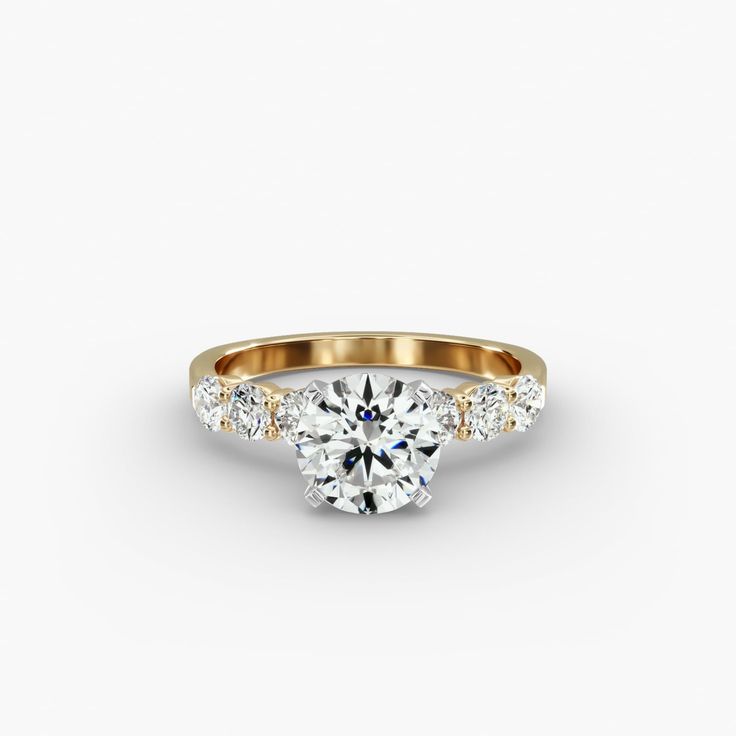 a gold engagement ring with three stones on the band and a round center stone in the middle