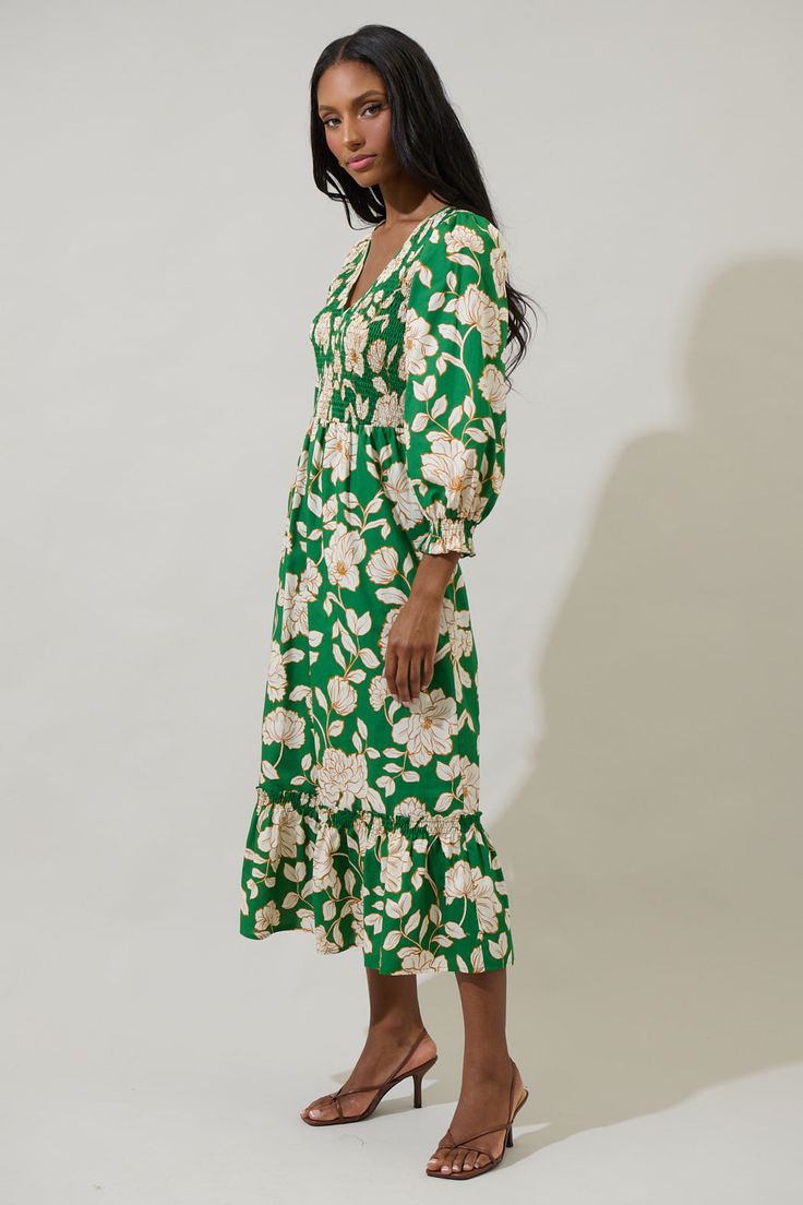 A season favorite list has to include the Lucena Floral Lemy Poplin Midi Dress. It features long sleeves, smocked bodice, and a v-neckline. The bottom has a ruffle hem tier. Wear it with matching ivory heels to create a full look. - Smocked- Deep V-neck- Floral- Lined- Color: Green MultiSize + Fit - Model is 5'10" and wearing size XS- Measurements taken from size S - Chest: 15 1/4"- Length: 49 3/4" Fabric Self: 100% Cotton, Lining: 97% Polyester 3% Spandex Style Number STD14589P Spring V-neck Smocked Dress For Daywear, V-neck Midi Dress With Smocked Bodice For Garden Party, Spring V-neck Dress With Smocked Cuffs, Green Spring Dress With Elastic Sleeves, Spring Green Dress With Elastic Sleeves, Green Midi Dress With Elastic Sleeves, Casual Green Dress With Elastic Sleeves, Green Long Sleeve Dress With Gathered Sleeves, Garden Party V-neck Midi Dress With Gathered Sleeves