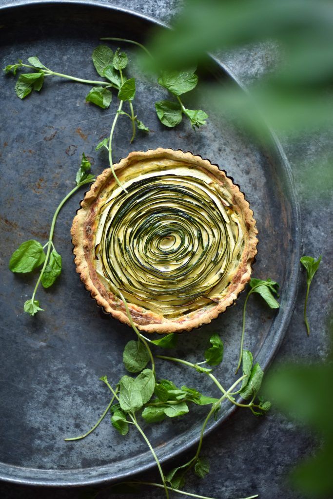 a quiche with spinach leaves on the side and an overhead view of it