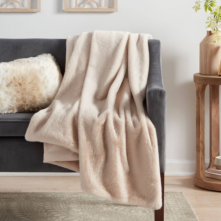 a couch with a blanket on top of it next to a table and potted plant