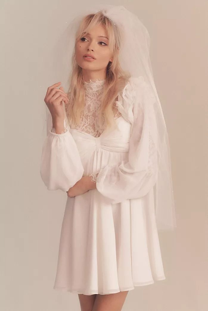 a woman in a white dress and veil posing for the camera with her hands on her hips