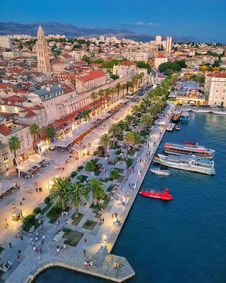 an aerial view of a city with boats in the water and people walking around it