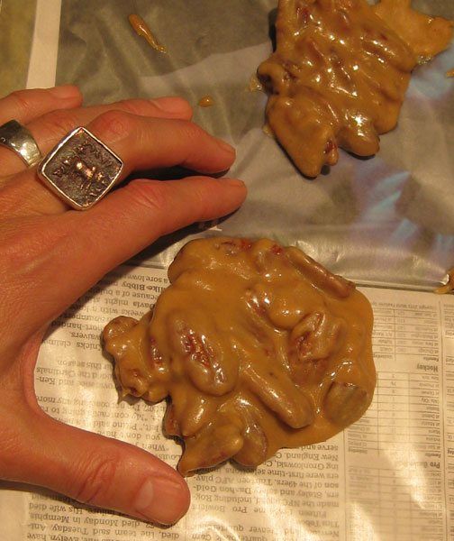 a person's hand holding two pieces of food on top of a piece of newspaper