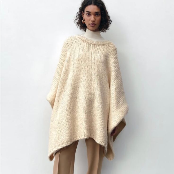 Ecru Cozy Sweater Poncho Casual Wool Poncho One Size, Casual Wool Poncho, Casual One-size-fits-all Wool Poncho, Oversized Chic Wool Poncho, Oversized Wool Poncho With Long Sleeves, Cream Winter Sweater One Size, Oversized Knitted Winter Cape, Oversized Beige Wool Sweater, Oversized Cape Sweater For Fall