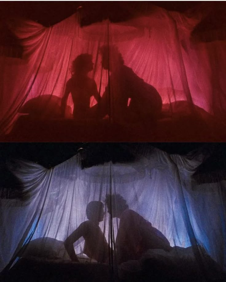 the silhouettes of two people sitting on a bed in front of a red curtain