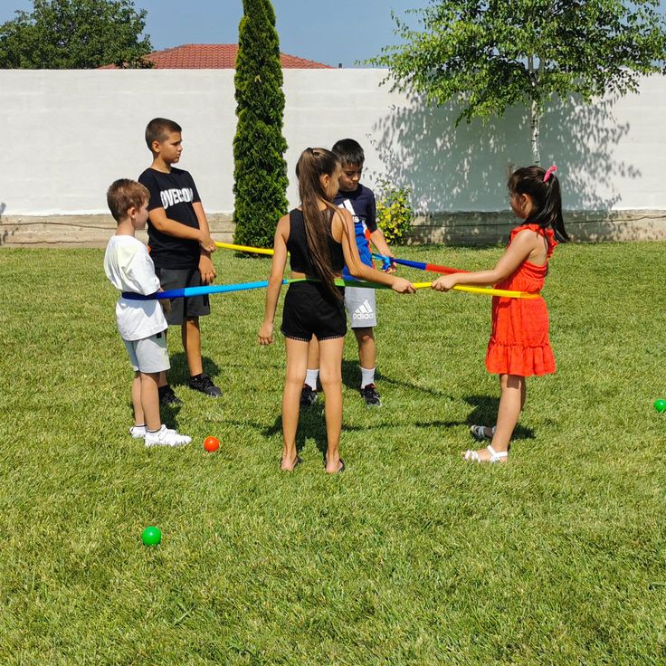 a group of children playing tug - ball in the grass