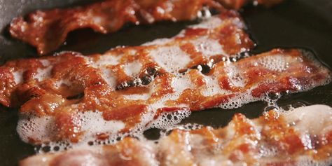 bacon being cooked in a frying pan with oil on it's side,