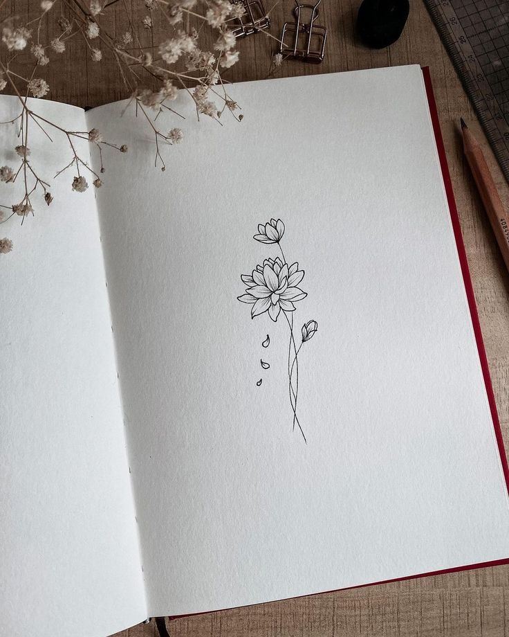 an open book with a drawing of flowers on it next to a pencil and scissors